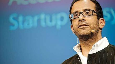 Rahul Sood steht vor einer blauen Leinwand, auf der die Worte Access und Startup zu lesen sind.