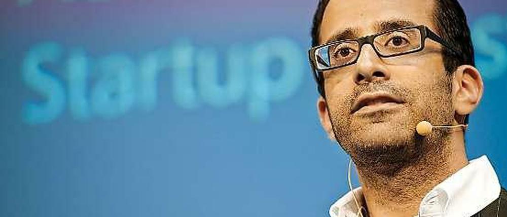 Rahul Sood steht vor einer blauen Leinwand, auf der die Worte Access und Startup zu lesen sind.