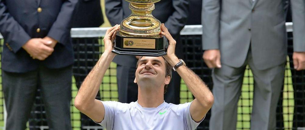 Roger Federer hält den Siegerpokal hoch.