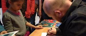 Generationsübergreifend: Der Zeichner Yoann verzaubert einen jungen Fan mit seiner Arbeit.