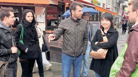 Die Kieze entdecken. Ares Kalandides (Mitte) führt die Chinesin Miao You (rechts) und andere Neuberliner aus aller Welt über den Wochenmarkt auf dem Winterfeldtplatz