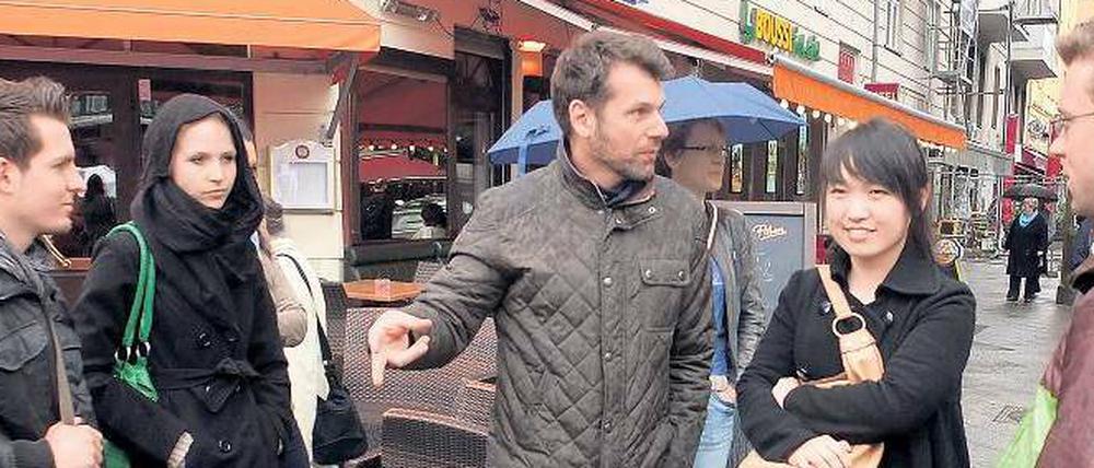Die Kieze entdecken. Ares Kalandides (Mitte) führt die Chinesin Miao You (rechts) und andere Neuberliner aus aller Welt über den Wochenmarkt auf dem Winterfeldtplatz