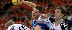 Melsungens Felix Danner (m.) wird von Kiels Aron Palmarsson (l.) und Kiels Marcus Ahlm in die Zangegenommen.