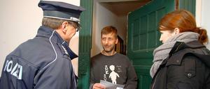 Ein Polizeibeamter und eine Polizeischülerin informieren einen Anwohner in Prenzlauer Berg, wie er seine Wohnung einbruchsicher machen kann.