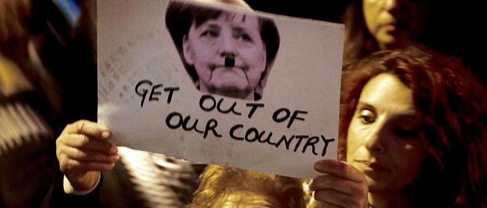 Bei einer Demonstration in Nikosia wird ein Bild von Bundeskanzlerin Angela Merkel mit angemaltem Hitlerbart in die Höhe gehoben.