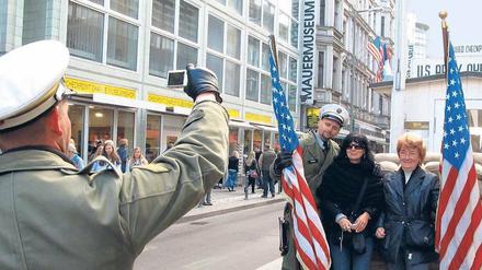 Bildabgleich. Touristinnen lassen sich am ehemaligen Grenzübergang Checkpoint Charlie mit Soldaten-Darstellern fotografieren.