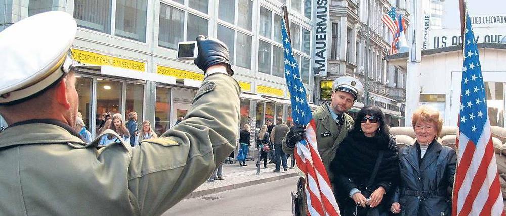 Bildabgleich. Touristinnen lassen sich am ehemaligen Grenzübergang Checkpoint Charlie mit Soldaten-Darstellern fotografieren.