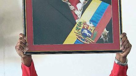 Gebete für den ewigen Präsidenten. Bei einem Gottesdienst hält ein Mann ein Chavez-Bild in die Höhe. Für Donnerstag sind Solidaritätskundgebungen geplant.