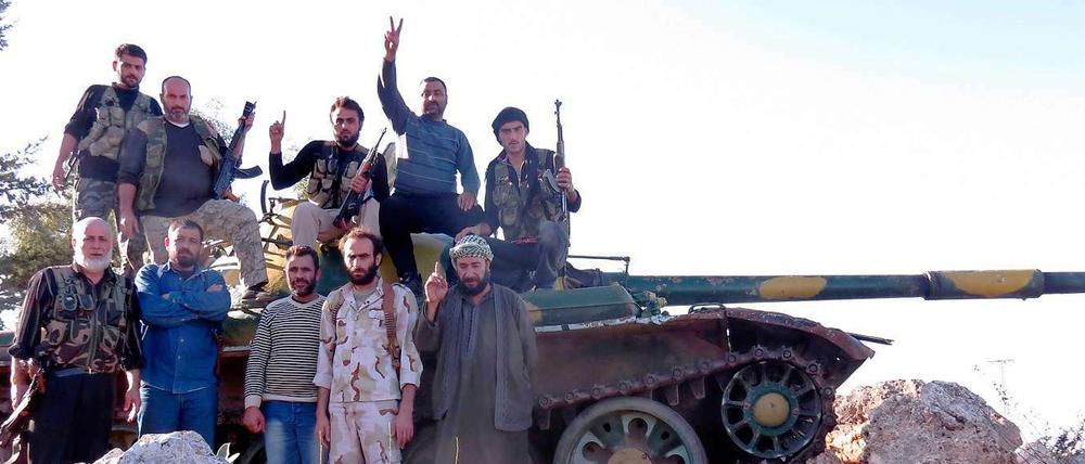 Rebellen der Freien Syrischen Armee posieren vor einem Panzer.