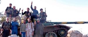 Rebellen der Freien Syrischen Armee posieren vor einem Panzer.