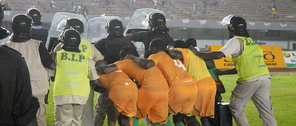 Kopf runter in Dakar. Nach ihrem 2:0-Sieg gegen den Senegal verlassen die Nationalspieler der Elfenbeinküste unter Polizeischutz den Platz.