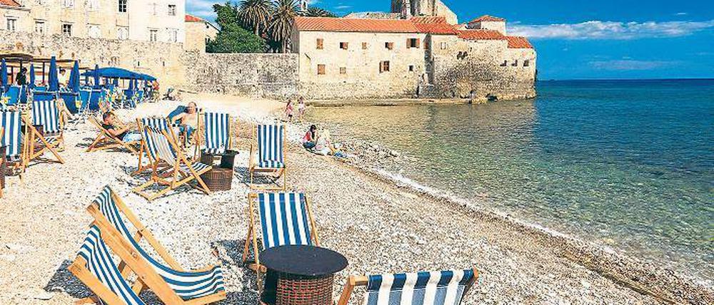 Baden vor historischer Kulisse. Kein Wunder, dass nur in der Vorsaison Liegestühle leer bleiben am Strand vor der Altstadt von Budva. Foto: Picture Alliance