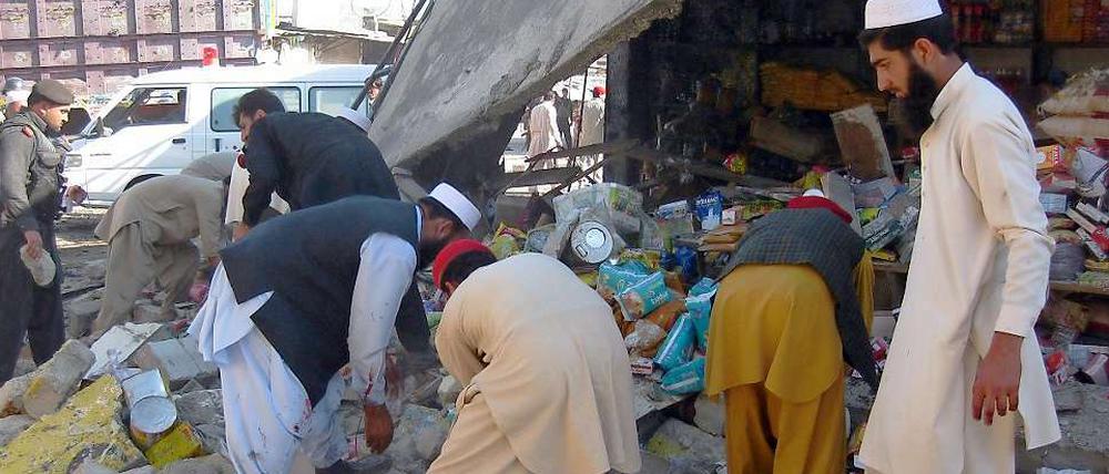 Pakistanische Sicherheitskräfte und Anwohner suchen nach dem Bombenanschlag nach Opfern.