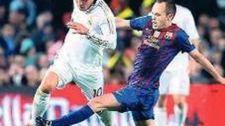 Klassisch gut. Reals Mesut Özil (vorn) läuft Andres Iniesta davon. Foto: dapd