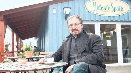 Haus gegen Pflanzen. Holger Zahn hat es sich auf der Terrasse seines Cafés bequem gemacht. Für den Bau hat er nicht einen Cent bezahlt. 