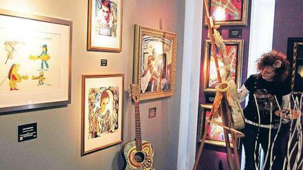 Das Leben ist eine Gitarre. Metall-Art-Künstlerin Birgit Poete bemalt in der Hofgalerie Instrumente, die am letzten Tag der Ausstellung „The Art of Hard Rock“ versteigert werden. Links eine Zeichnung von Panikrocker Udo Lindenberg von 2010. Foto: Davids/Sven Darmer