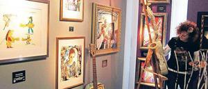 Das Leben ist eine Gitarre. Metall-Art-Künstlerin Birgit Poete bemalt in der Hofgalerie Instrumente, die am letzten Tag der Ausstellung „The Art of Hard Rock“ versteigert werden. Links eine Zeichnung von Panikrocker Udo Lindenberg von 2010. Foto: Davids/Sven Darmer