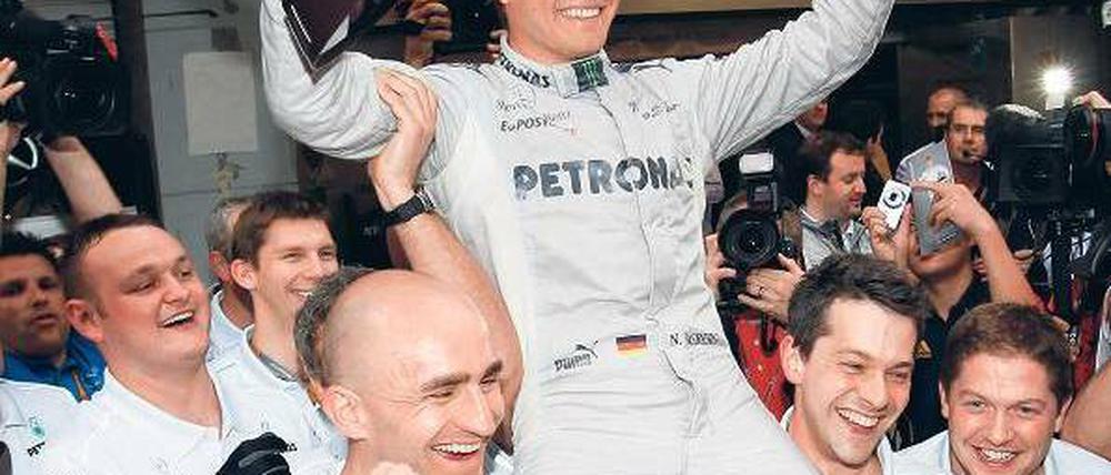 Pose mit Pott. Für seinen ersten Sieg wird Nico Rosberg auf Händen getragen. Foto: dapd