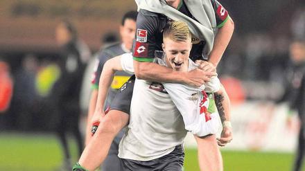 Oben bleiben. Marco Reus hat noch Kraft, Torschütze Mike Hanke zu tragen. Foto: AFP