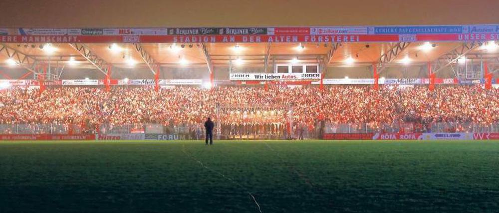 Dann singt mal schön. Die Fußballer vom Zweitligisten 1. FC Union sind schon aus dem DFB-Pokal ausgeschieden, die Fans strömen trotzdem ins Stadion. Mit Kerze und Gesangsbuch. Foto: dpa