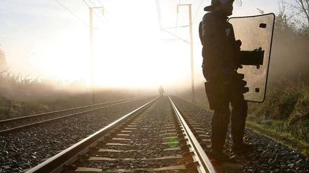 Polizisten sichern die Bahnstrecke, auf der der Castor-Transport rollen wird.
