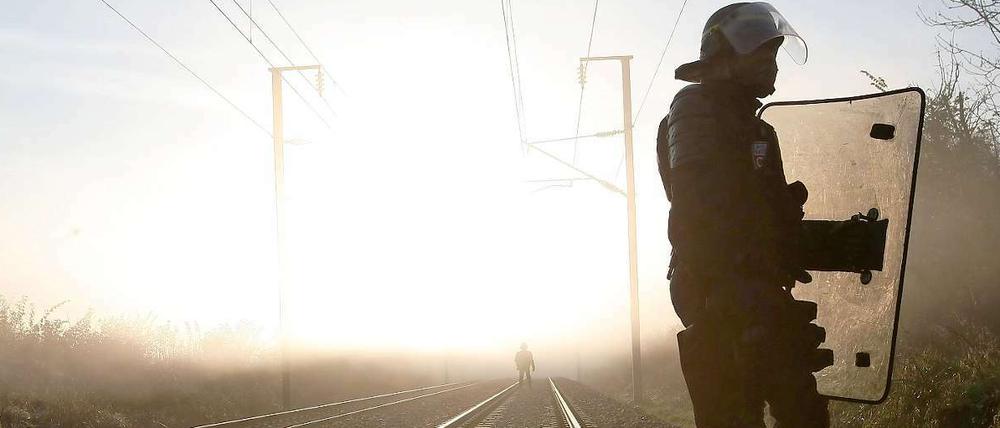 Polizisten sichern die Bahnstrecke, auf der der Castor-Transport rollen wird.