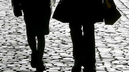 Eine Mutter läuft mit ihrer Tochter an der Hand die Straße entlang.