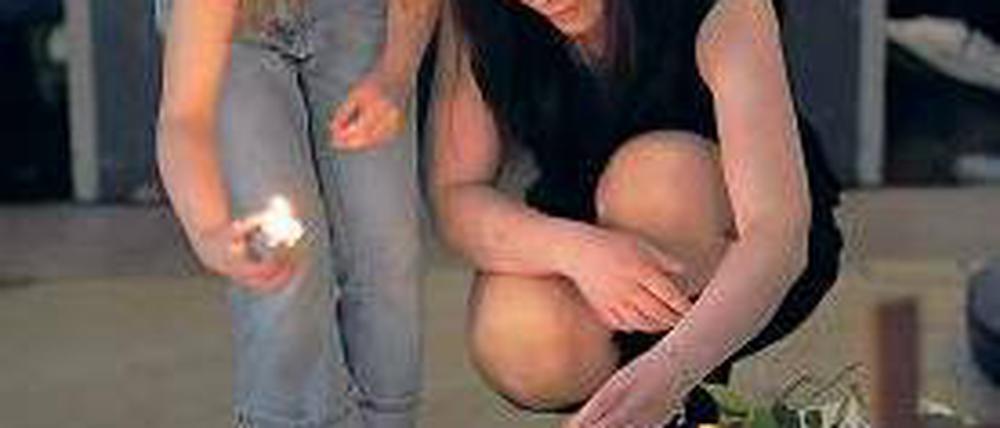 Trauernde zünden Kerzen an und legen Blumen nieder.