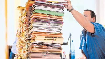 Vor dem Aktenberg. Über Arbeitsmangel können die Mitarbeiter der Behörden wirklich nicht klagen. Über zu wenig Personal für die Papierstapel aber schon. Foto: Gottschalk/dapd