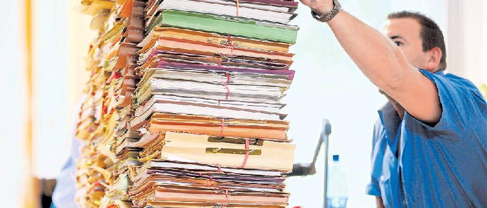 Vor dem Aktenberg. Über Arbeitsmangel können die Mitarbeiter der Behörden wirklich nicht klagen. Über zu wenig Personal für die Papierstapel aber schon. Foto: Gottschalk/dapd