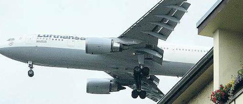 Flugzeug fliegt knapp über einem Haus in der Einflugschneise vom Flughafen Tegel.