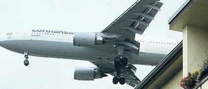 Flugzeug fliegt knapp über einem Haus in der Einflugschneise vom Flughafen Tegel.