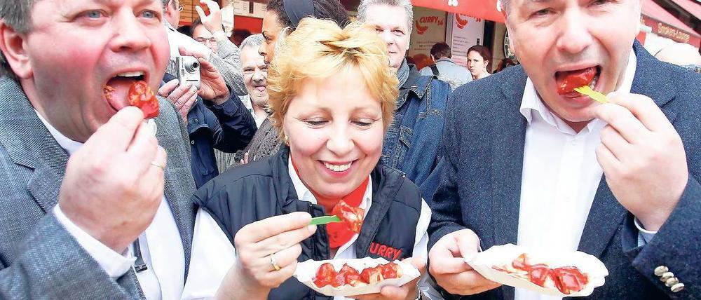 Curry-36-Inhaber Lutz Michael Stenschke, Chefin Vera Stenschke und Klaus Wowereit lassen sich eine Currywurst schmecken.
