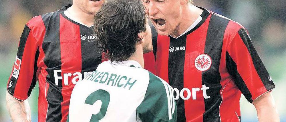 Nichts für sensible Gemüter. Im Abstiegskampf kann man schon mal seine gute Erziehung vergessen. Hier muss sich Arne Friedrich der beiden Frankfurter Marco Russ (l.) und Maik Franz erwehren. Der Wolfsburger flog nach diesem Wortgefecht mit Gelb-Rot vom Platz. Foto: dapd