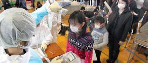 Geordnetes Anstehen: Kinder in Fukushima werden Mit Strahlenmessgeräten untersucht.