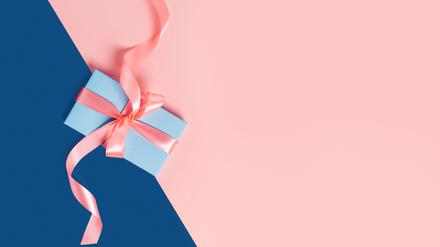 Greeting card with one gift box on classic blue background. Pink bows. Central composition. Flat lay, top view.