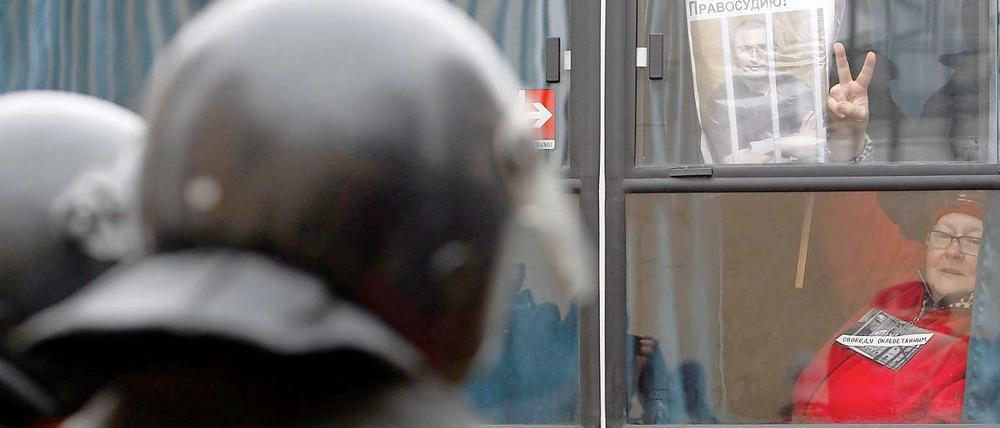 Eine Demonstrantin für den Ex-Oligarchen Michail Chodorkowski zeigt das Victory-Zeichen aus einem Polizei-Bus vor dem Gerichtsgebäude in Moskau.