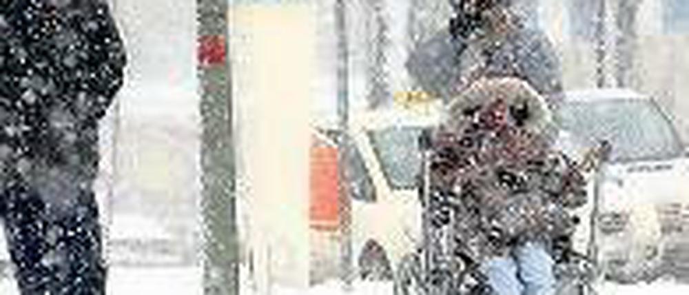 Bescheidene Wünsche. Die winterlich verschneite Stadt macht vielen das Leben schwer. Ältere Menschen bleiben derzeit aus Vorsicht lieber drinnen, und wer einen Behinderten im Rollstuhl zu bewegen hat, muss Schwerstarbeit leisten. Foto: Kumm/dpa