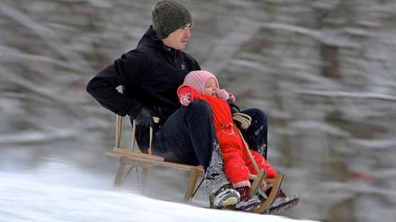 Ein Vater rodelt mit seinem Sohn den Berg herunter.