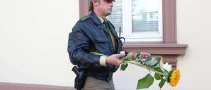 Ein Polizist trägt in Lörrach vor dem Wohnhaus der Amokläuferin Blumen und Kerzen. Vier Menschen starben beim Amoklauf von Sabine R.. Sie selbst wurde von Polizisten erschossen, um Schlimmeres zu verhindern.