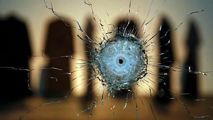 Glasbruch. Die Arbeit "A Hole" (2010), dahinter die sieben Mäntel von "Coats" mit Einschusslöchern.