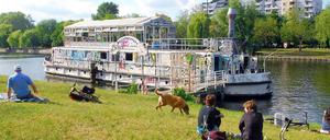 Idylle oder Ärgernis? Am Urbanhafen sitzen die Kreuzberger gern in der Sonne. Viele Uferwanderer können jedoch beim Anblick des verwahrlosten "Theaterschiffs Tau" schwer entspannen.