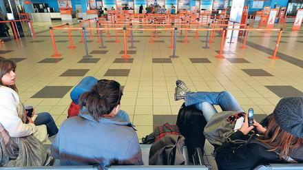 Bankdrücker in Schönefeld. Vorteil: Warteschlangen gibt es nicht. Nachteil: Man kommt trotzdem nicht voran. Junge Touristen teilen per SMS mit, dass sie später kommen.