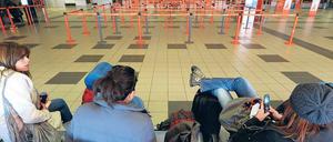 Bankdrücker in Schönefeld. Vorteil: Warteschlangen gibt es nicht. Nachteil: Man kommt trotzdem nicht voran. Junge Touristen teilen per SMS mit, dass sie später kommen.