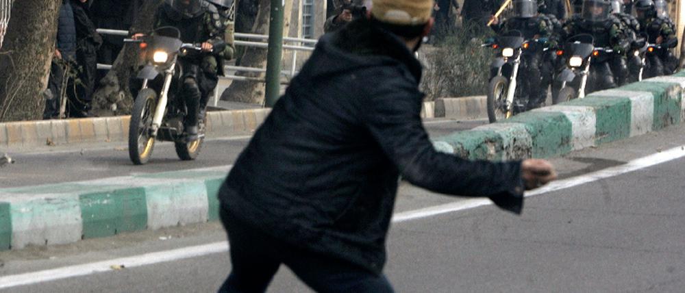 An Iranian protester throws a stone at riot police during fierce clashes in central Tehran
