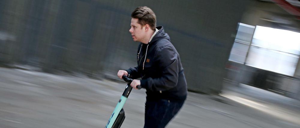 Ein Mann fährt auf einem Testgelände mit einem Elektro Roller (E-Scooter).