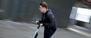 Ein Mann fährt auf einem Testgelände mit einem Elektro Roller (E-Scooter).