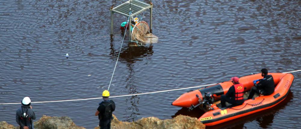 Ein Taucher wird in einem Baggersee unter Wasser gelassen, um dort nach weiteren Leichenteilen zu suchen.