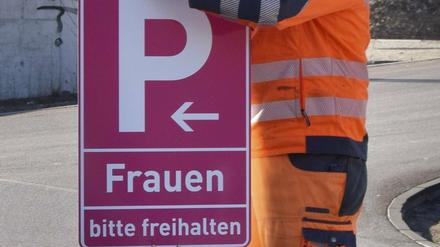 Ein Mitarbeiter der Stadt montiert an einem Parkplatz ein neues, pinkfarbenes Frauenparkplatzschild. (Archiv 2019)