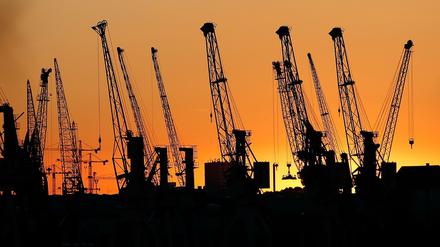 Die Sonne geht hinter Hafenkränen in Hamburg unter. In der Eurozone hat sich die Konjunktur nach Einschätzung der OECD deutlich abgekühlt. (Symbolbild)